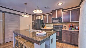 A kitchen with dark wood cabinets, a granite countertop, a stainless steel refrigerator, and a built-in oven. - Pet-Friendly Home w/ Deck in Broken Bow! (Broken Bow)