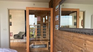 A room with a wooden wall, a bed, a chair, and a glass door leading to an outdoor area. - 6 pers Holiday home Aurora with directly on the Lauwersmeer (Anjum)