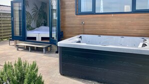 A modern house with a sliding glass door leading to a bedroom, a hot tub, and a wooden exterior. - 6 pers Holiday home Aurora with directly on the Lauwersmeer (Anjum)