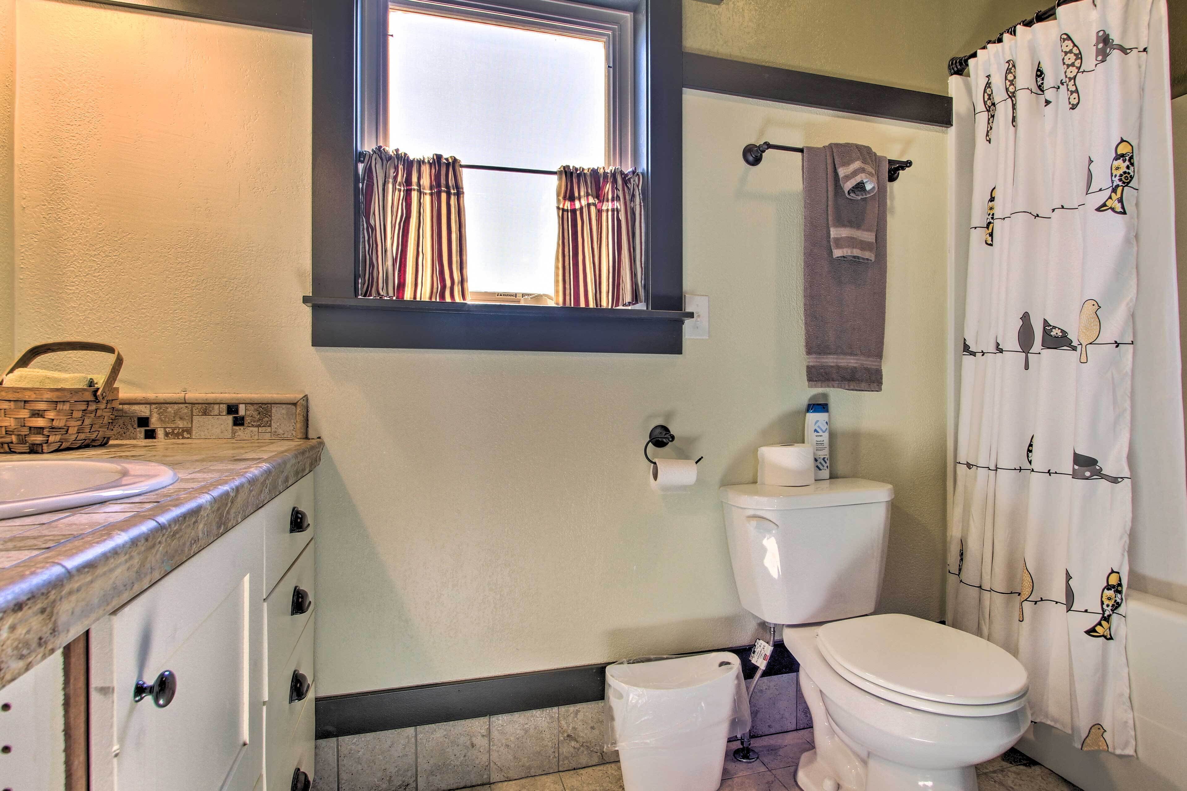 Un baño con inodoro, lavamanos y ventana con cortinas.