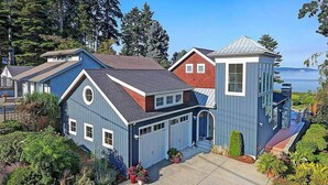 A residential property with a garage, a covered porch, and a view of the water.