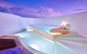 A modern indoor swimming pool with a curved design, a small seating area with a cushion, and a staircase leading to a higher level. - Calla Villa (Hengchun)