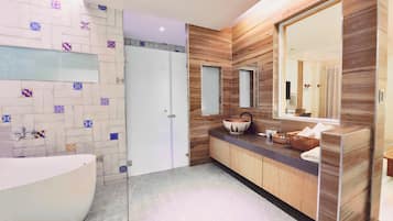 Une salle de bain moderne avec une baignoire sur pieds, un meuble-lavabo en bois doté d’un grand miroir et un pare-feu en carreaux.
