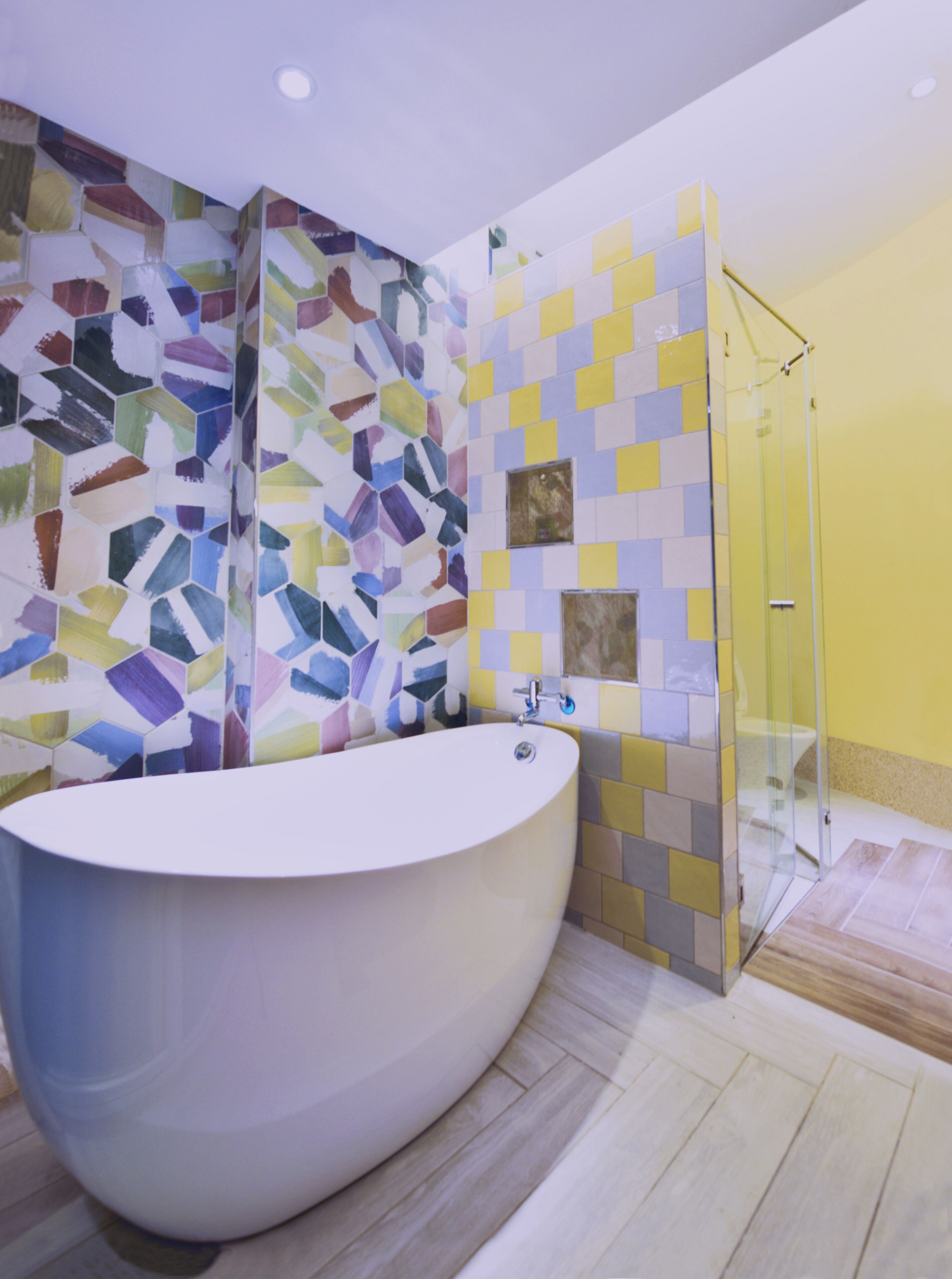 Un baño moderno con una bañera independiente, cabina de ducha con mampara de vidrio y pared de mosaicos.