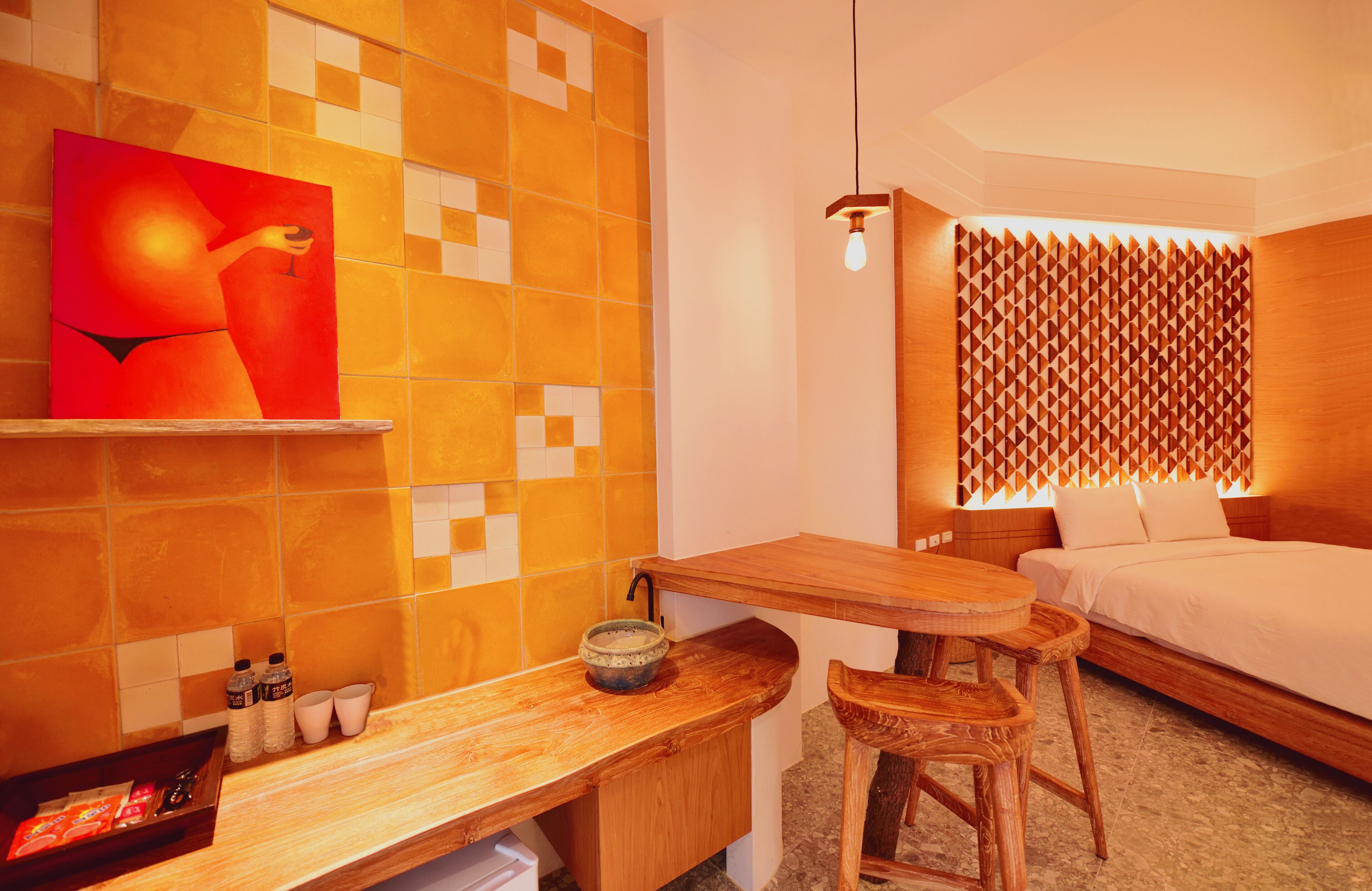 Habitación de hotel con un escritorio de madera, una cama, un estante con un cuadro y un panel acústico estampado.