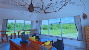Una habitación amplia con ventanas grandes, una mesa de comedor de madera y asientos cómodos.