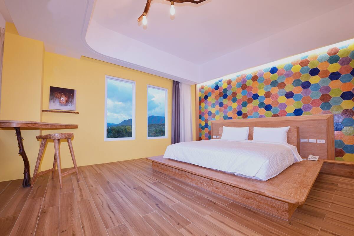Una camera da letto con un letto e un tavolo in legno, e un design murale esagonale dai colori vivaci.