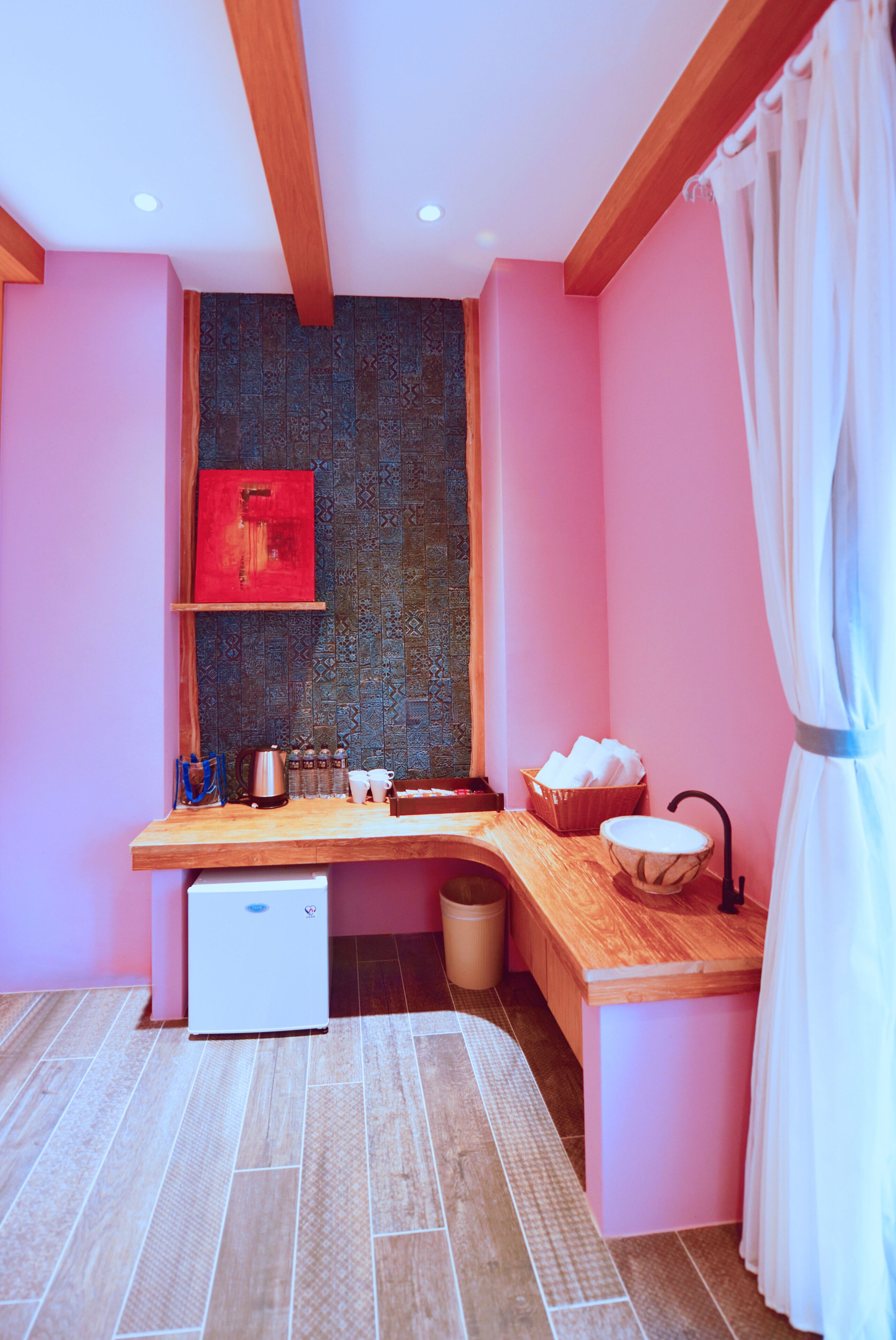 A compact kitchen with a wooden countertop, a small refrigerator, and a patterned backsplash.