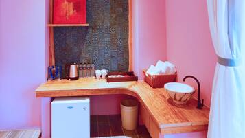 A compact kitchen with a wooden countertop, a small refrigerator, and a patterned backsplash.
