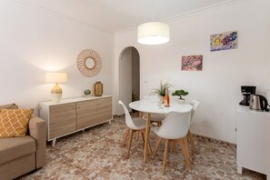 Un salon moderne comprenant une table à manger, des chaises, un canapé, un meuble, une lampe et des œuvres d’art accrochées aux murs.
