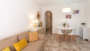 Un espace de vie comprenant un canapé, une table à manger avec des chaises, une lampe et un petit meuble.