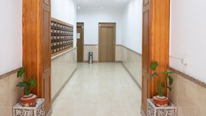 Un couloir avec des portes en bois, une poubelle et des plantes en pot.