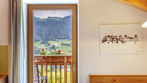 A room with a wooden door leading to a balcony with a view of a mountainous landscape. - Holiday Apartment "Dolomiten Winklerhof" with Mountain View, Garden & Wi-Fi (Villanders)