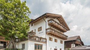 A multi-story building with balconies, a large tree, and a sign reading 'Winklerhof.'