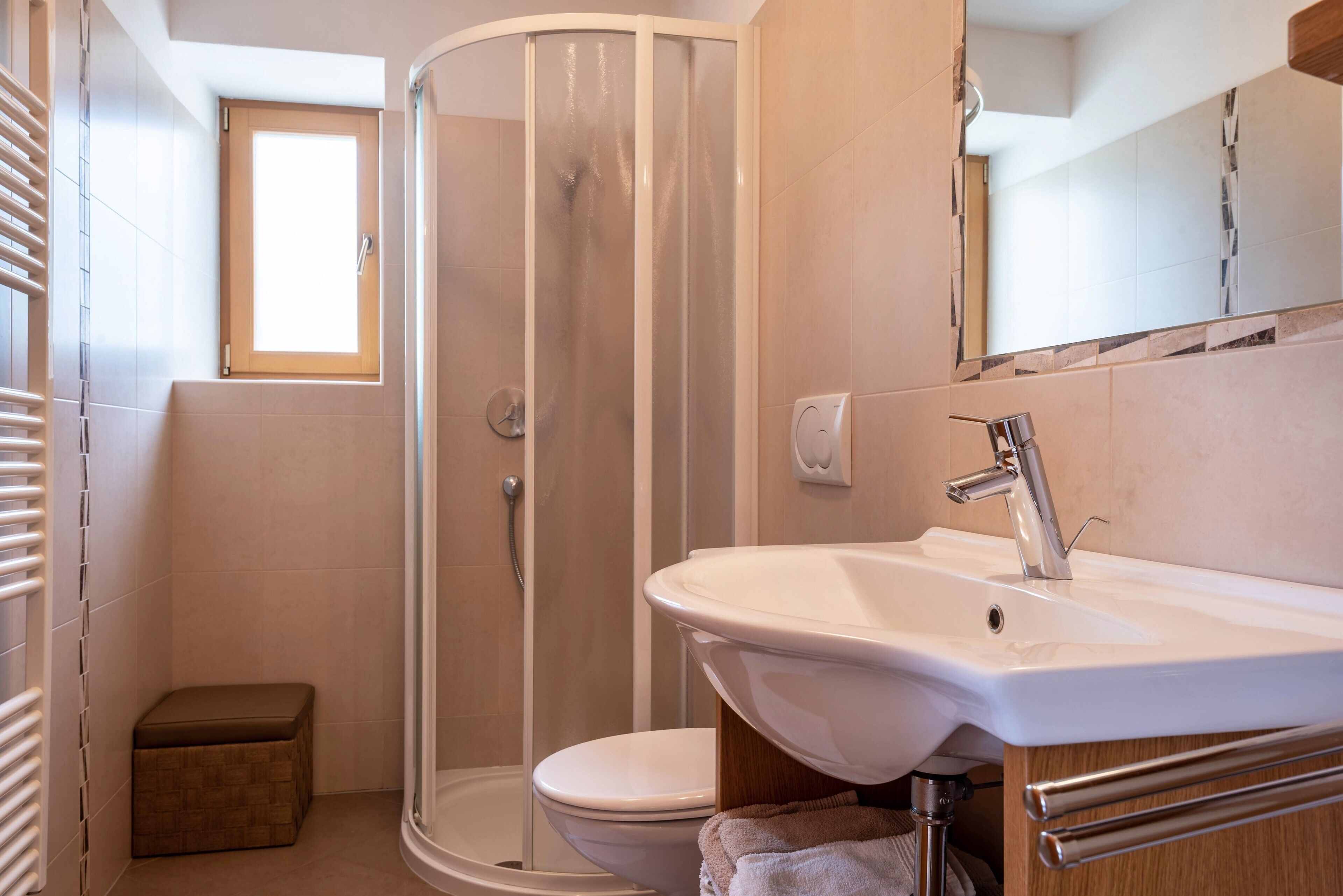 Ein Badezimmer mit Dusche, Toilette, Waschbecken und einem Fenster.