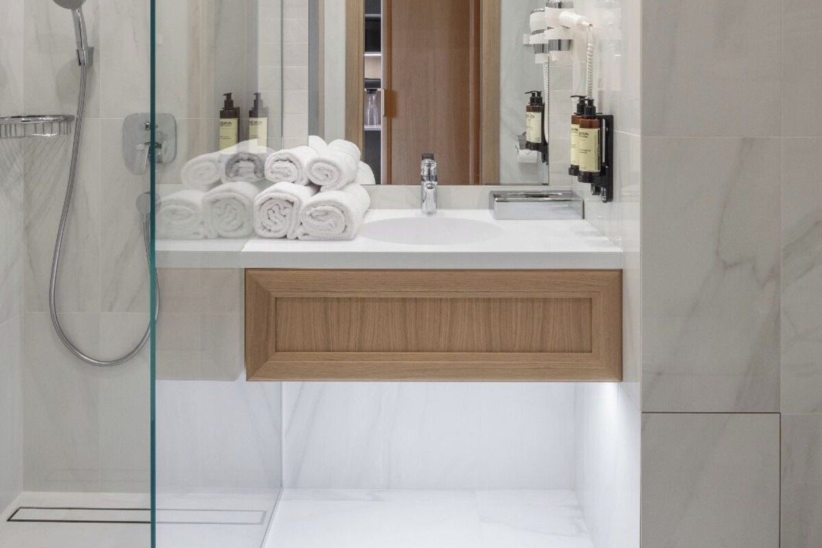 A modern bathroom with a glass shower enclosure, a wooden vanity, and a large mirror.