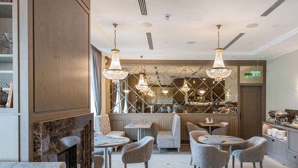Un comedor moderno con suelo de mármol, asientos acolchados y candelabros de cristal.