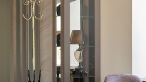 Un interior moderno con una zona de estar, un aparador de vidrio y un elegante atril para paraguas.