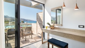 A balcony with a view of a pool and mountains, a wooden table with chairs, and pendant lighting.