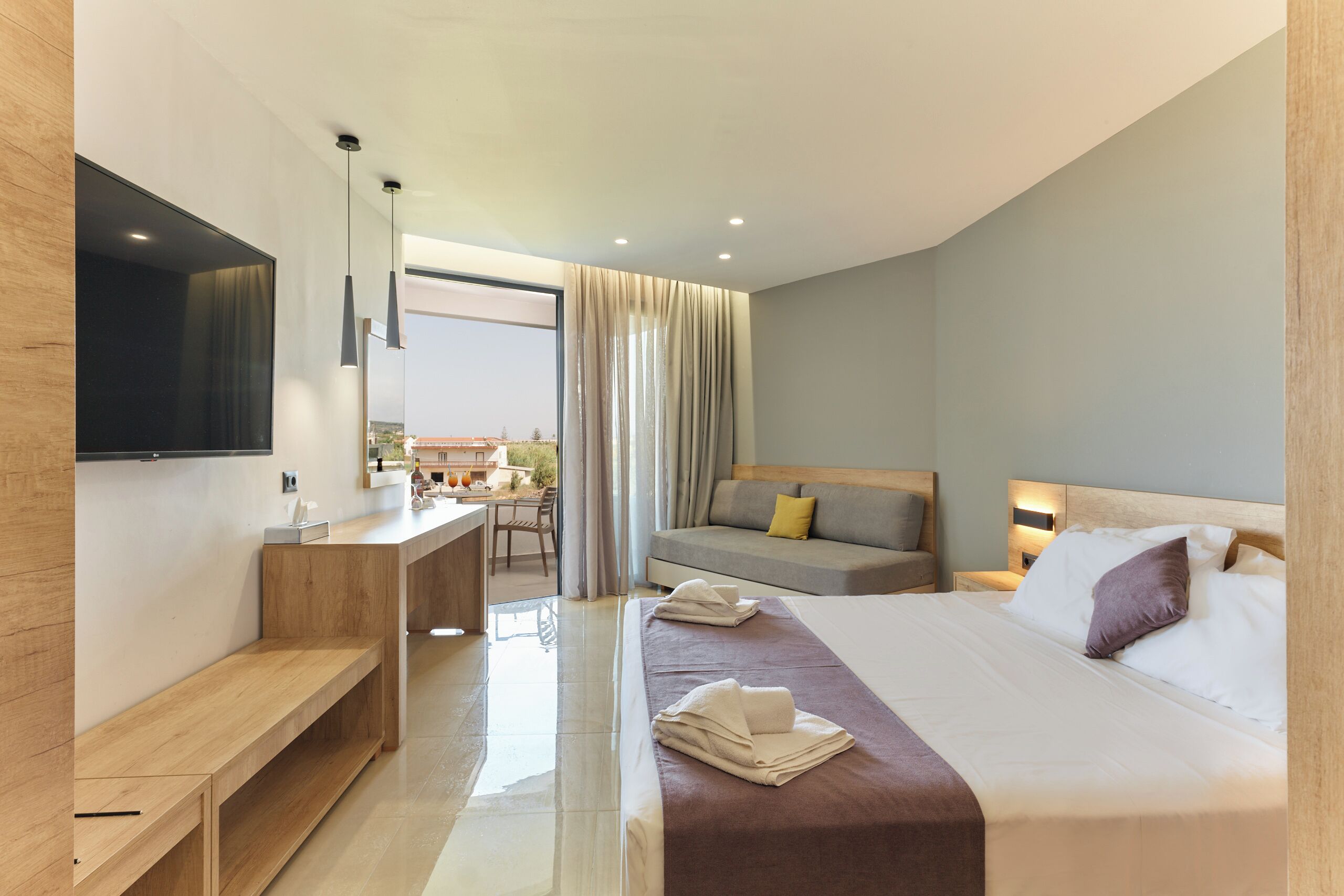 A modern hotel room with a bed, bedside table, and a view of the city.