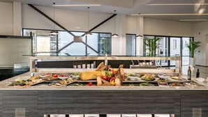 A modern buffet setup with various food items and a glass partition.