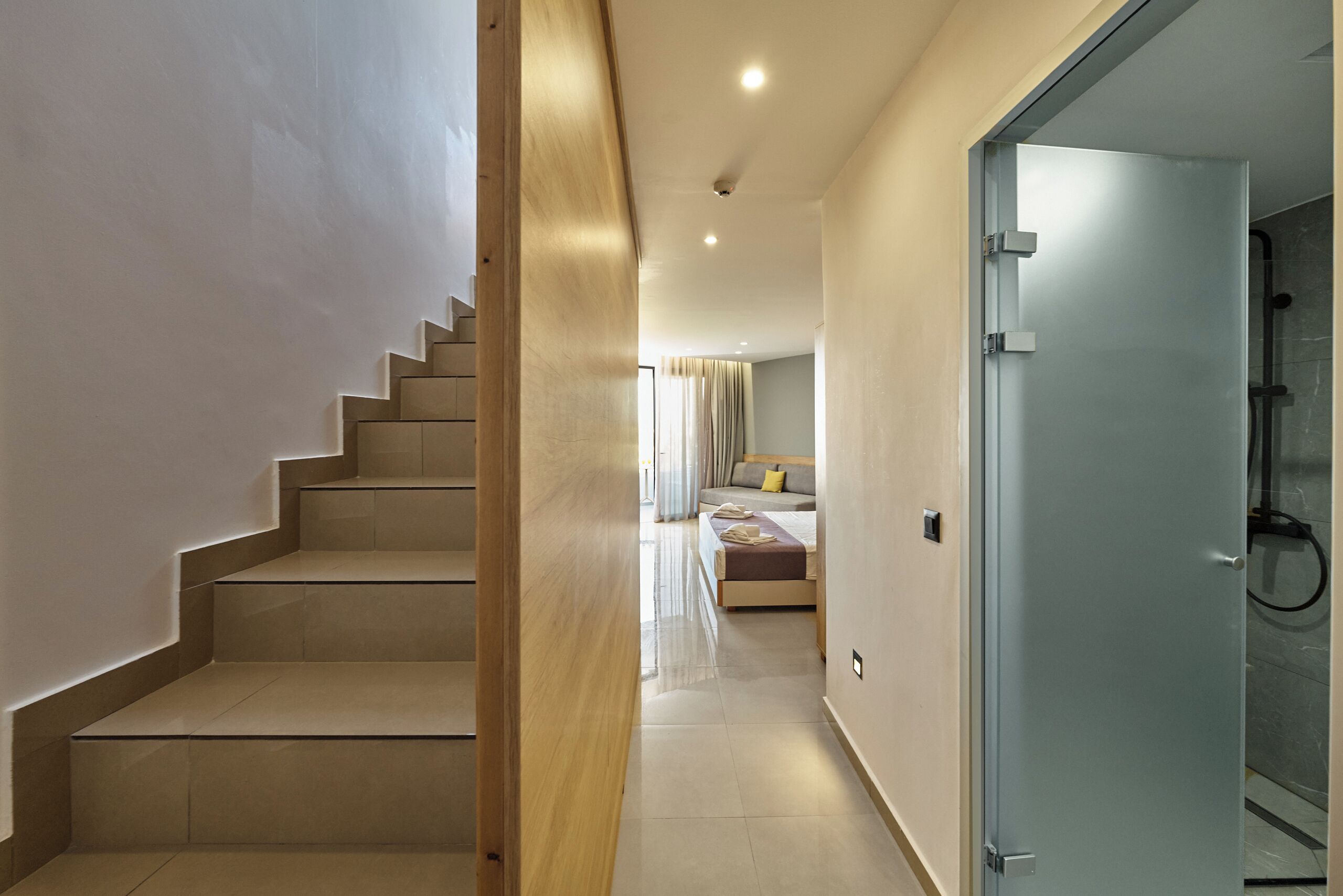 A modern hotel room with a staircase, a bed, and a bathroom.