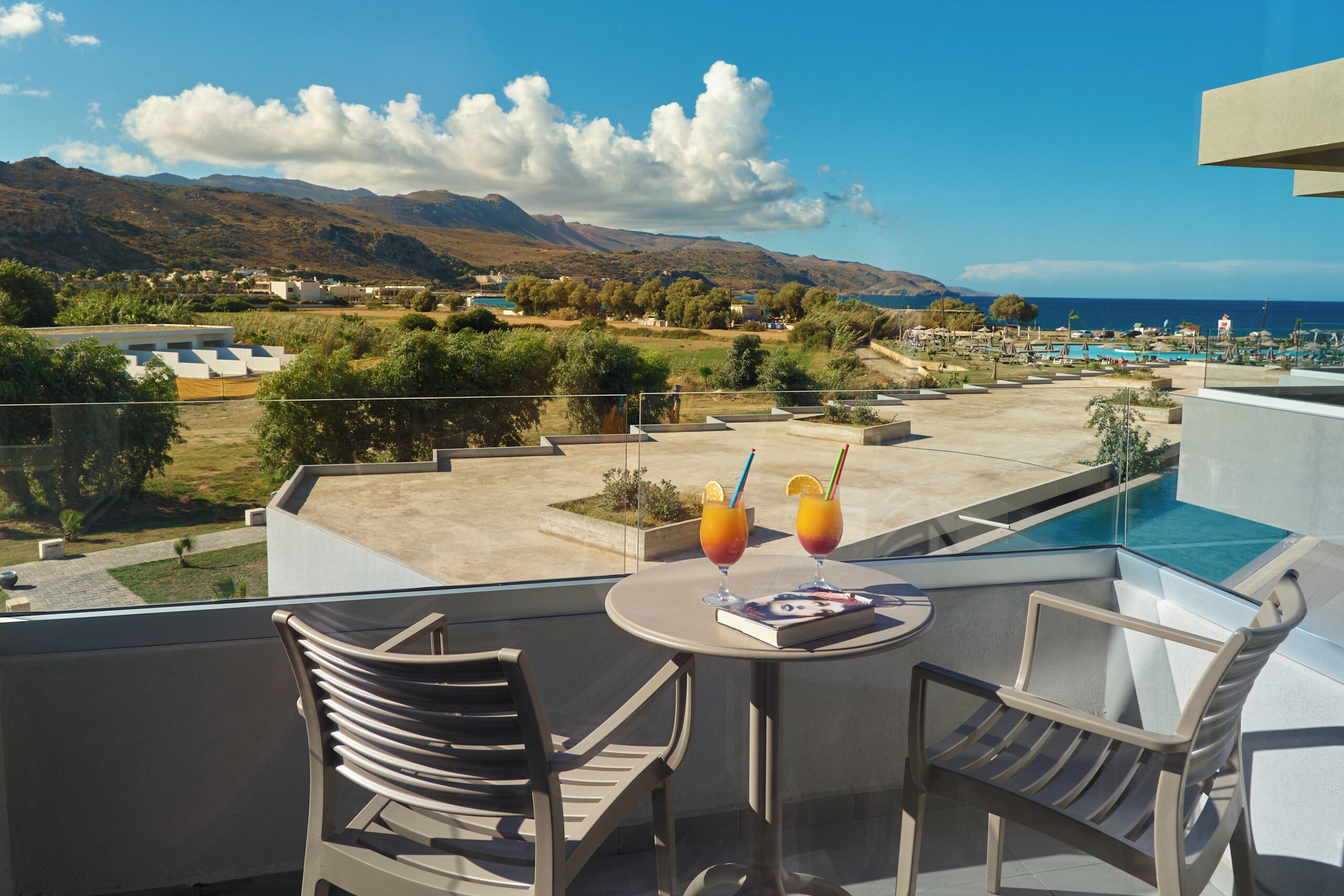 Un balcon avec une table, deux chaises et deux boissons.