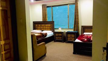 Relax in this cozy space with two single beds, a sofa, and a table, offering a view of the outside through the window.