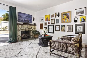 Una sala de estar con chimenea de piedra, un televisor de pantalla plana grande y varias obras de arte enmarcadas en las paredes.