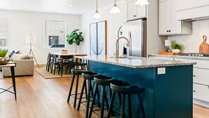 A modern kitchen with a central island, bar stools, and pendant lighting. - Rock n' Relax at Desert Color by RedAwning (St. George)