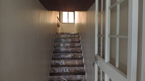 Una escalera con escalones de mármol que conduce a una puerta con paneles de vidrio.