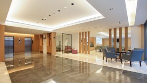 A spacious lobby with a polished marble floor, a seating area with chairs, and a reception desk. - Sitara Hotel Apartment (Dubai)