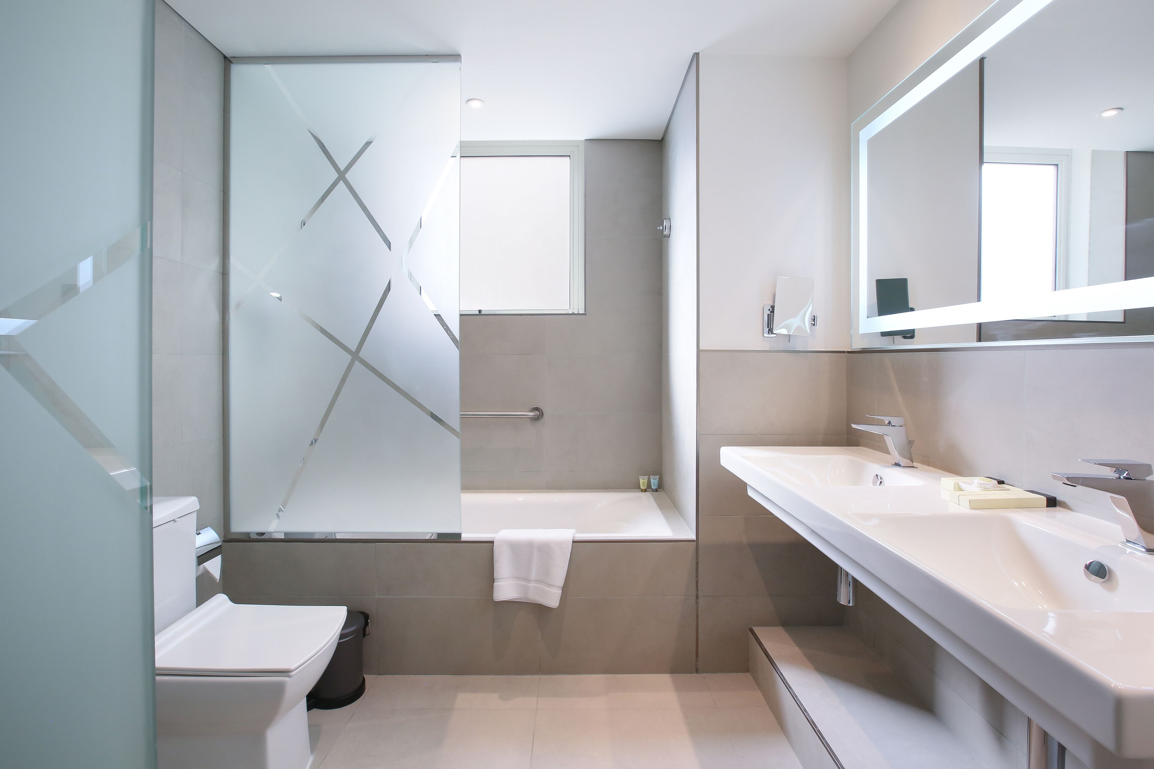 Un baño moderno con cabina de ducha de vidrio, bañera y dos lavabos.