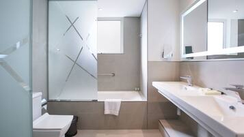 Un baño moderno con cabina de ducha de vidrio, bañera y dos lavabos.