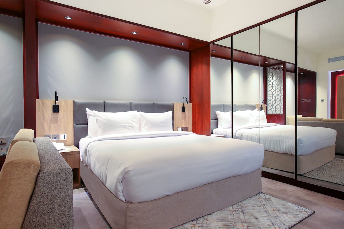 Une chambre d’hôtel moderne dotée d’un grand lit, d’un coin salon et d’un grand miroir.