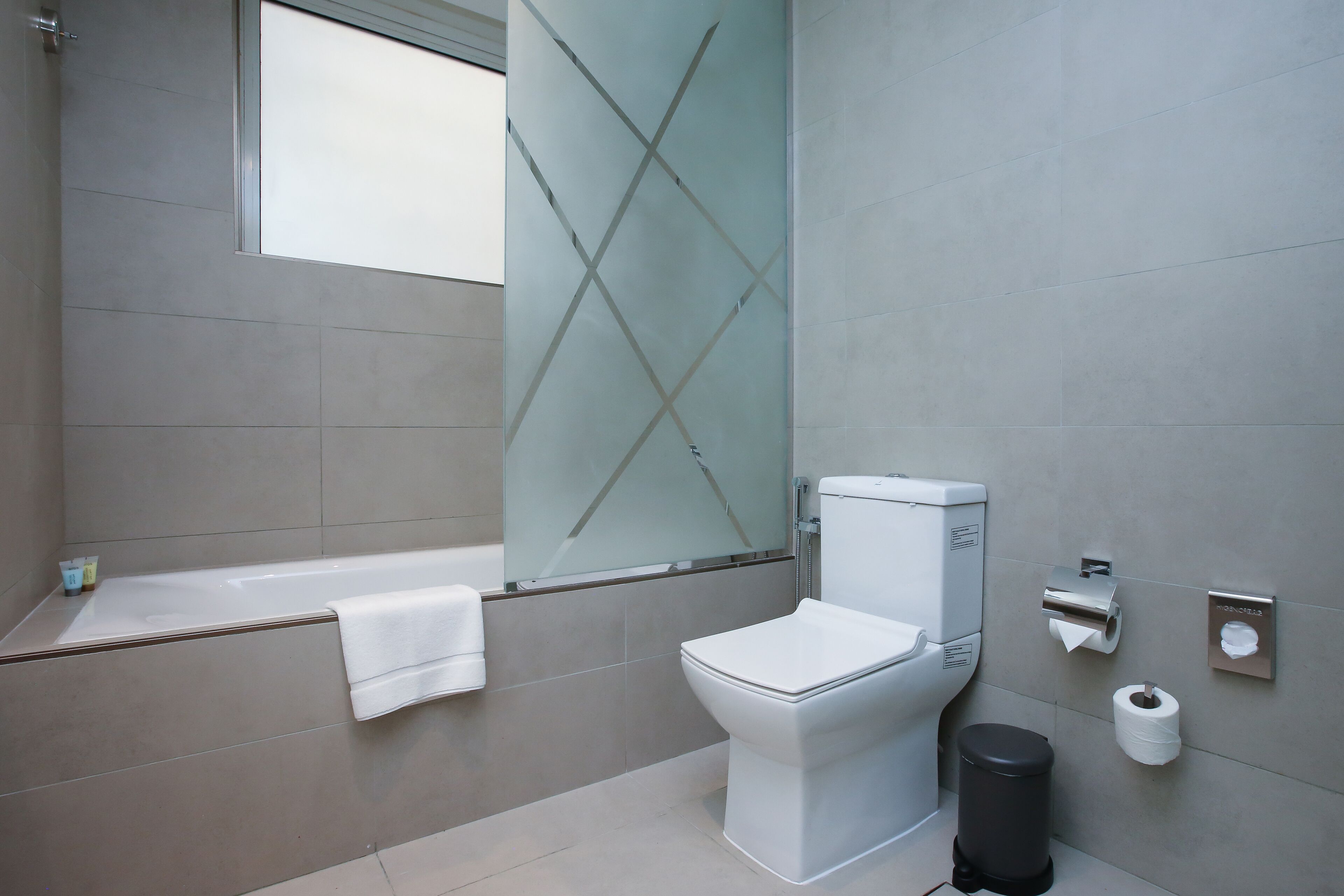 Un bagno moderno con vasca, WC e box doccia in vetro.