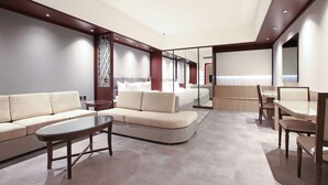 A modern hotel room with a sofa, a glass-top coffee table, a dining table with chairs, and a large mirror. - Sitara Hotel Apartment (Dubai)