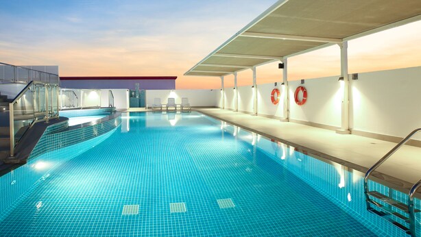 An indoor swimming pool with clear blue tiles, a covered seating area, and lifebuoys on the wall. - Sitara Hotel Apartment (Dubai)