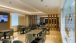 A modern conference room with tables and chairs, a large screen, and a glass partition with a view. - Sitara Hotel Apartment (Dubai)
