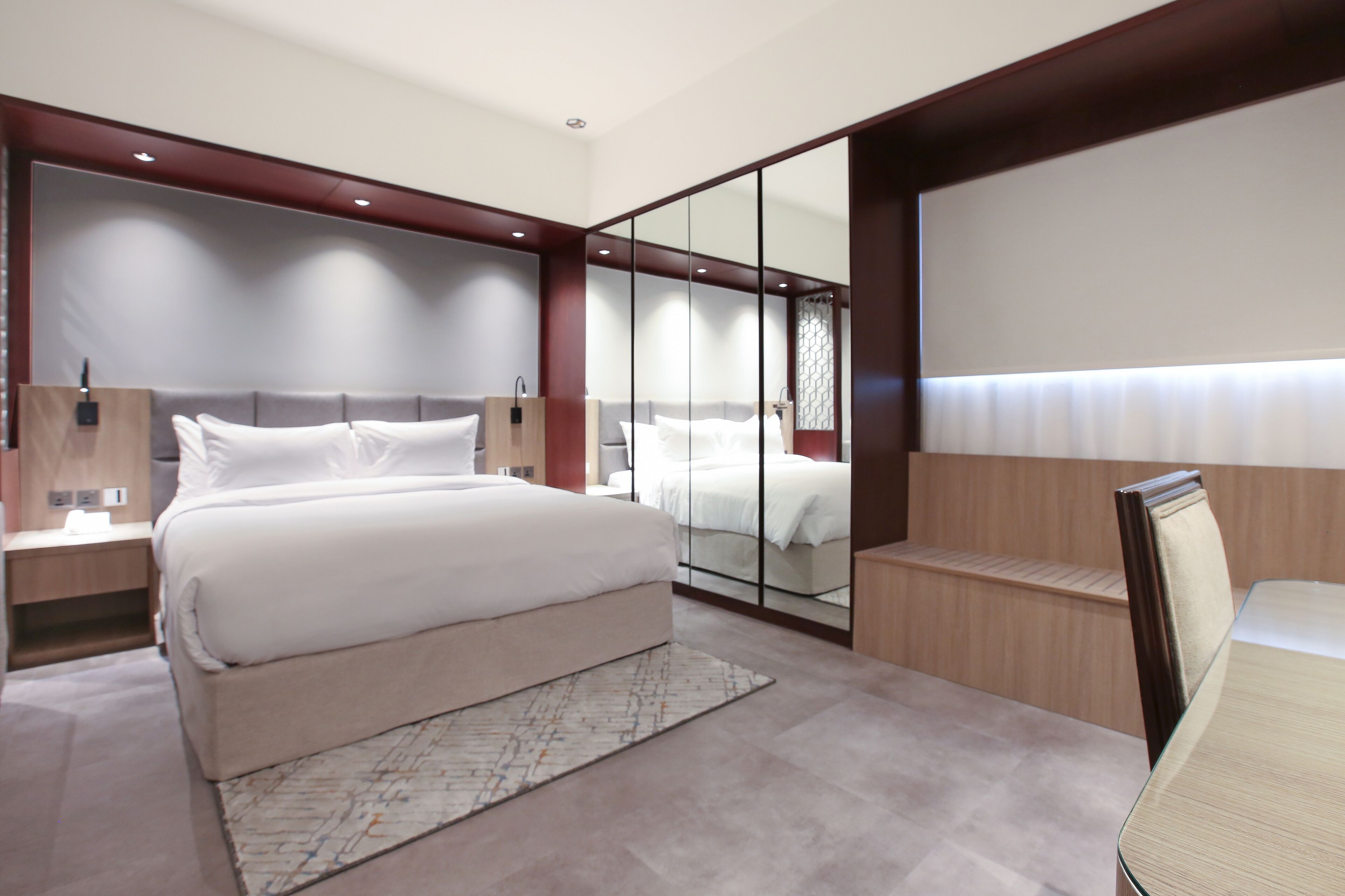 Une chambre moderne avec un grand lit, des tables de chevet, un miroir et un coin salon.