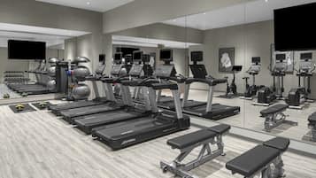 A modern gym with treadmills, elliptical machines, and weight stations.