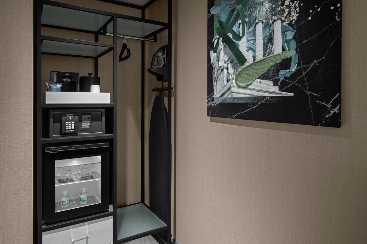 A hotel room with a minibar, a refrigerator, and a marble-patterned wall.