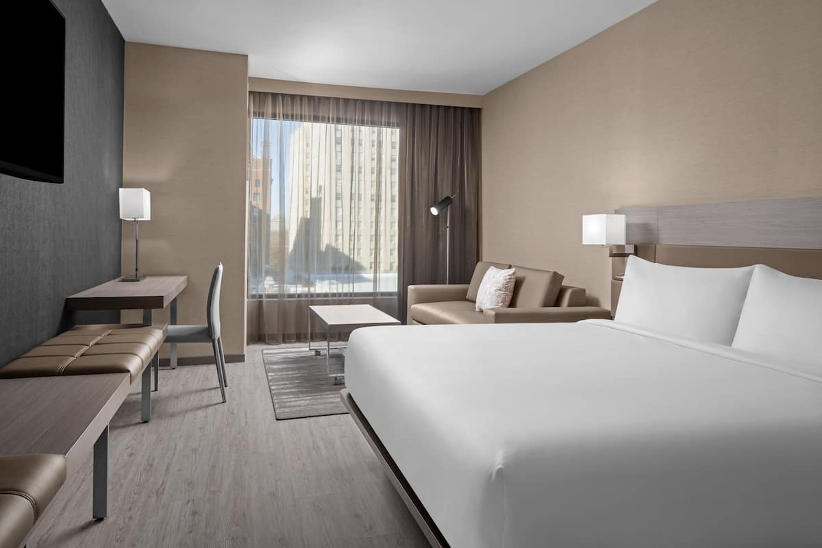 Una habitación de hotel moderna con una cama grande, un sofá, un escritorio y una silla.