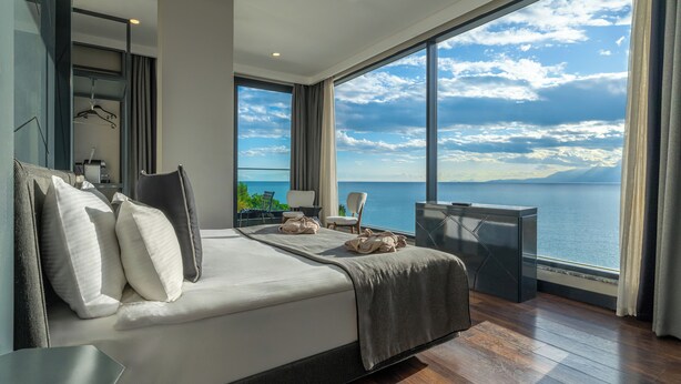 Une chambre moderne avec un grand lit, un bureau et une vue sur la mer.