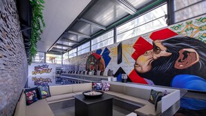 Uma área de estar moderna com uma mesa de centro preta, almofadas coloridas e um mural de um macaco.
