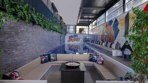 Un espace de détente moderne avec un mur en pierre, un ensemble de canapés, un foyer et une fresque murale.