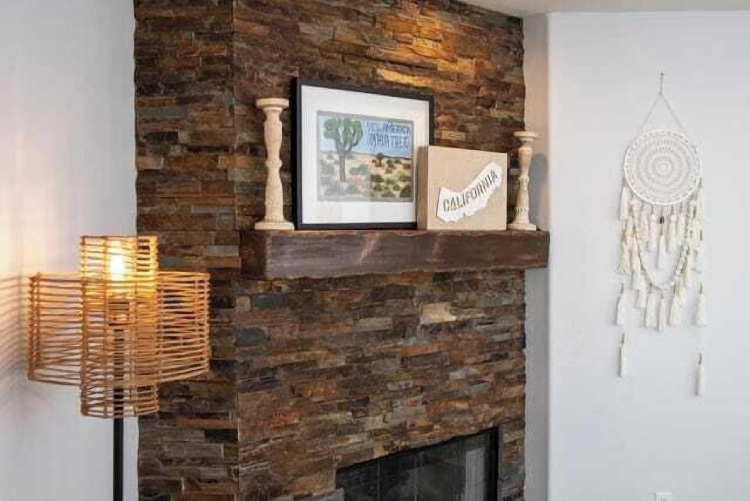 A fireplace with a stone facade, a framed picture, a 'California' sign, and a dreamcatcher.