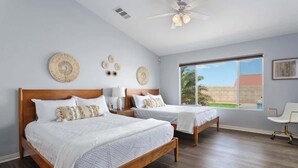A bedroom with two beds, a ceiling fan, and a large window with a view of the outside. - ❤️Modern 4BR Joshua Tree House w/ heated Pool! (Yucca Valley)
