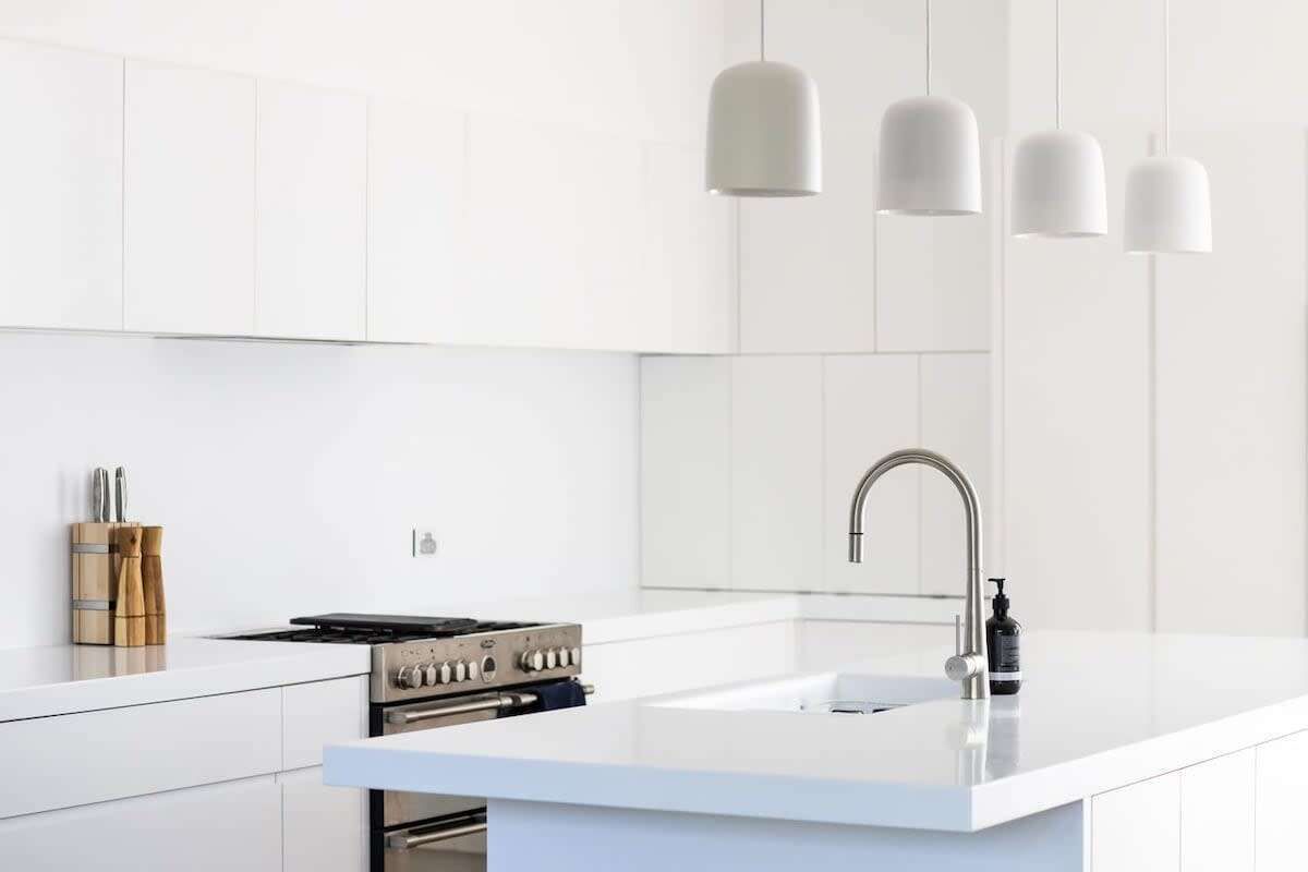 A modern kitchen with white cabinetry, a stainless steel stove, and pendant lighting.