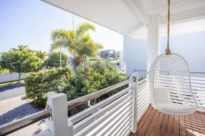 A balcony with a hanging chair, white railings, and a view of greenery and buildings. - Casa De Palmeras (CASUARINA)